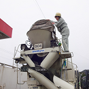 ミキサー車のホッパーカバーを閉じるドライバー