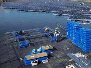 フロート式水上太陽光発電システムのユニットを組み立てる作業員