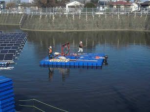 ポンツーン船で水上作業台に戻る作業員